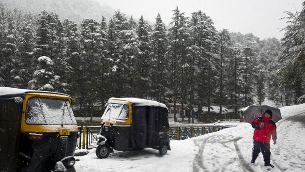 An auto-rickshaw driver walks past the parked vehicles as it snows in Dharamshala, Himachal Pradesh. (Ashwini Bhatia / AP) An auto-rickshaw driver walks past the parked vehicles as it snows in Dharamshala, Himachal Pradesh. (Ashwini Bhatia / AP)