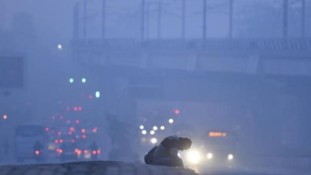 A man sits as vehicles drive pass amid dense fog on a winter morning at Kirti Nagar, in New Delhi. (Sanchit Khanna / HT Photo) A man sits as vehicles drive pass amid dense fog on a winter morning at Kirti Nagar, in New Delhi. (Sanchit Khanna / HT Photo)