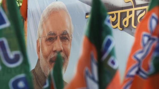Bharatiya Janata Party (BJP) workers carry flags past a poster of Prime Minister Narendra Modi during an event to celebrate the reservation bill passed in Parliament, Mumbai, January 10. (AFP) Bharatiya Janata Party (BJP) workers carry flags past a poster of Prime Minister Narendra Modi during an event to celebrate the reservation bill passed in Parliament, Mumbai, January 10. (AFP)