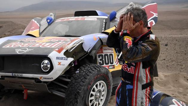 Mini’s Spanish driver Carlos Sainz of Spain gestures next to his car after stopping due to a crash during Stage 3. Reigning champion Carlos Sainz was 23rd and four hours and 40 minutes off the leader’s pace after a nightmare stage on Wednesday. (Franck Fife / AFP) Mini’s Spanish driver Carlos Sainz of Spain gestures next to his car after stopping due to a crash during Stage 3. Reigning champion Carlos Sainz was 23rd and four hours and 40 minutes off the leader’s pace after a nightmare stage on Wednesday. (Franck Fife / AFP)
