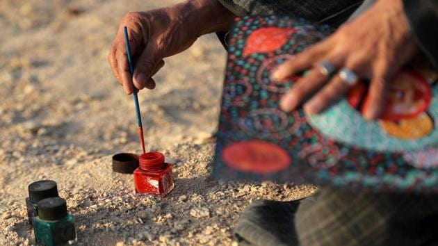 El-Shark dips his brush into handcrafted colour. “The making of colours is a very simple process. I did not come up with it myself. I took it from the creator’s world, from nature, a little from the mountains and the greenery, and then I made the material that fixes the colours,” he said. (Mohamed Abd El Ghany / REUTERS)