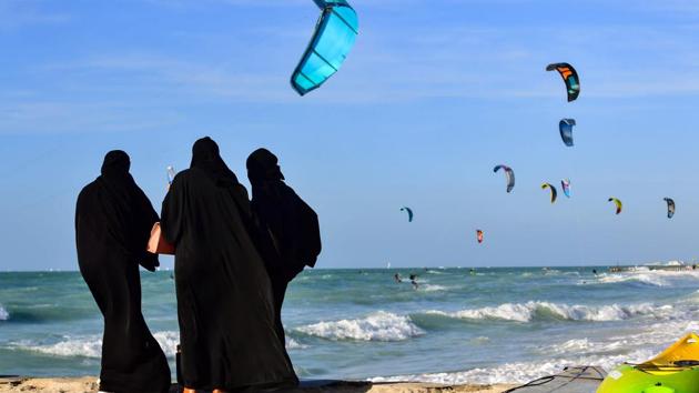 Women wearing abayas stand on a beach as they watch kitesurfers in the water in Dubai, United Arab Emirates. (Guiseppe Cacace / AFP) Women wearing abayas stand on a beach as they watch kitesurfers in the water in Dubai, United Arab Emirates. (Guiseppe Cacace / AFP)