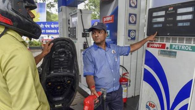 An employee shows the revised prices of petrol and diesel to a customer at a fuel station.(PTI)