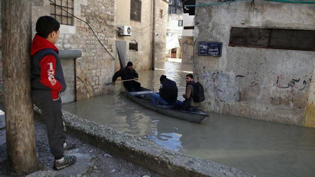 A child stands watching a small boat manoeuvrers along a flooded street in the town of Darkush. Civilians who have fled other parts of Syria recaptured by government forces make up around half of the resident population of Idlib and neighbouring rebel-held areas. (Aaref Watad / AFP)