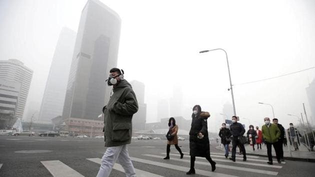 A man wearing a respiratory protection mask walks toward an office building during the smog after a red alert was issued for heavy air pollution in Beijing's central business district, China.(Reuters)