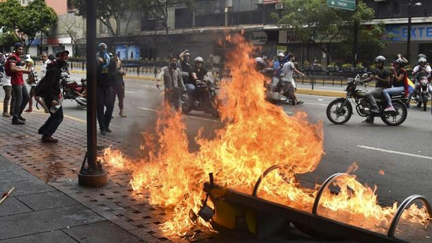 A protester burns a motorcycle during clashes with the security forces. Maduro’s reelection last year was contested by the opposition, and criticised internationally -- but the socialist leader has until now retained the loyalty of the powerful military, whose response was being keenly watched. (Yuri Cortez / AFP) A protester burns a motorcycle during clashes with the security forces. Maduro’s reelection last year was contested by the opposition, and criticised internationally -- but the socialist leader has until now retained the loyalty of the powerful military, whose response was being keenly watched. (Yuri Cortez / AFP)
