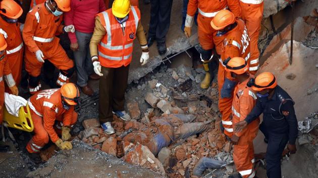 Rescue workers recover a body from the debris after a four-storey building collapsed in Ullawas area of Gurugram, early Thursday morning, Jan 24, 2019.(PTI)