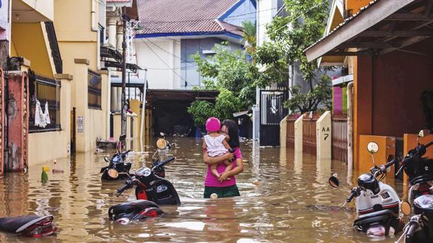 A woman carries her daughter as she wades through a flooded neighborhood in Makassar, South Sulawesi, Indonesia. (Yusuf Wahil / AP) A woman carries her daughter as she wades through a flooded neighborhood in Makassar, South Sulawesi, Indonesia. (Yusuf Wahil / AP)