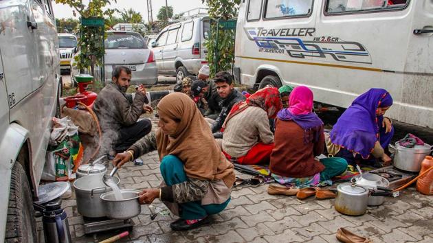 Stranded passengers prepare a meal on a pavement after Jammu-Srinagar highway remained closed due to heavy snowfall in Jammu.(PTI)