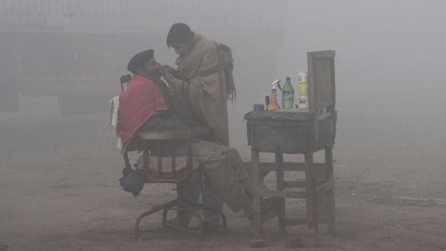 A Pakistani barber shaves a customer alongside a road amid heavy fog and smog conditions in Lahore, Pakistan. (Arif Ali / AFP) A Pakistani barber shaves a customer alongside a road amid heavy fog and smog conditions in Lahore, Pakistan. (Arif Ali / AFP)