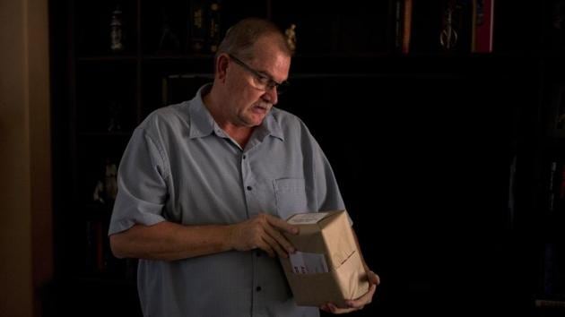 Doug Biggers looks at the unopened package that contains his son’s ashes. The ashes sat on the kitchen counter for months in the same box they’d picked up from the crematorium, still wrapped in brown parchment paper, “like a raw salmon,” his daughter had observed. They considered sprinskling them in the ocean, but then he’d be gone forever. (Jae C. Hong / AP) Doug Biggers looks at the unopened package that contains his son’s ashes. The ashes sat on the kitchen counter for months in the same box they’d picked up from the crematorium, still wrapped in brown parchment paper, “like a raw salmon,” his daughter had observed. They considered sprinskling them in the ocean, but then he’d be gone forever. (Jae C. Hong / AP)
