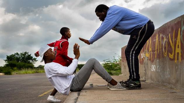 Youths help each other run through their morning exercise routine. On the road over a railway track outside the Zimbabwean city of Bulawayo, about 30 people from surrounding townships go through their morning exercise routines daily. (Zinyange Auntony / AFP) Youths help each other run through their morning exercise routine. On the road over a railway track outside the Zimbabwean city of Bulawayo, about 30 people from surrounding townships go through their morning exercise routines daily. (Zinyange Auntony / AFP)