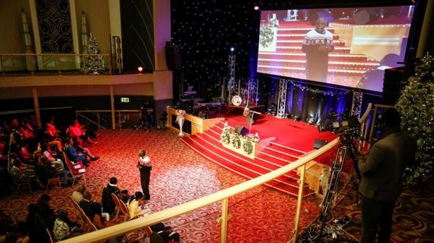 A cameraman films Pastor Andrew Adeleke as he speaks during 'Super Sunday' service at the House of Praise church in London. Hymns are sung only in African languages in some temples, or only in English at others. Some pastors take worshippers for full immersion baptisms in the cold of the English Channel. Others believe that when congregants suddenly start speaking in unknown languages it marks the presence of the Holy Spirit. (Simon Dawson / REUTERS) A cameraman films Pastor Andrew Adeleke as he speaks during 'Super Sunday' service at the House of Praise church in London. Hymns are sung only in African languages in some temples, or only in English at others. Some pastors take worshippers for full immersion baptisms in the cold of the English Channel. Others believe that when congregants suddenly start speaking in unknown languages it marks the presence of the Holy Spirit. (Simon Dawson / REUTERS)