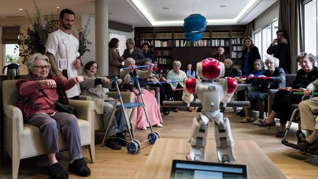 Elderly people take part in activities led by a humanoid robot named Zora during a presentation to the press on the occasion of the nationwide launch of the service at a Maisons de Famille retirement home (EPHAD) in Paris, France. (Philippe Lopez / AFP)