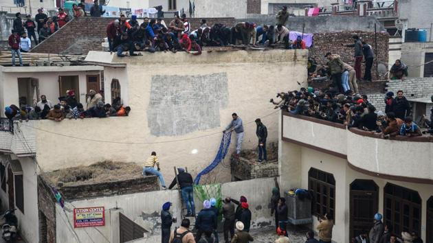 Forest Department workers try to catch the leopard while local residents look on from rooftops. The sedated animal was put in a cage and taken to Chhatbir zoo. Officials said it would remain under observation for several days before deciding its future. (Shammi Mehra / AFP)