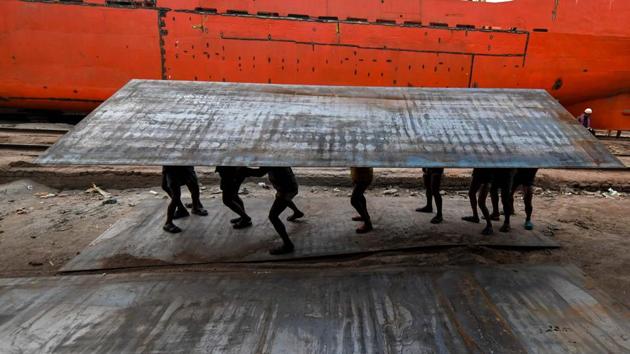 Bangladeshi labourers carry a heavy steel plate in a dockyard beside the Buriganga river in Dhaka. (Munir Uz Zaman / AFP)