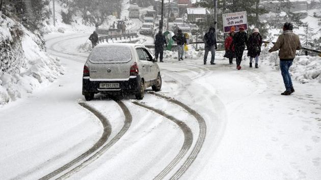 Vehicles move slowly on the snow covered Dhalli-Kufri highway during fresh snowfall, in Shimla, Himachal Pradesh. (Deepak Sansta / HT Photo)