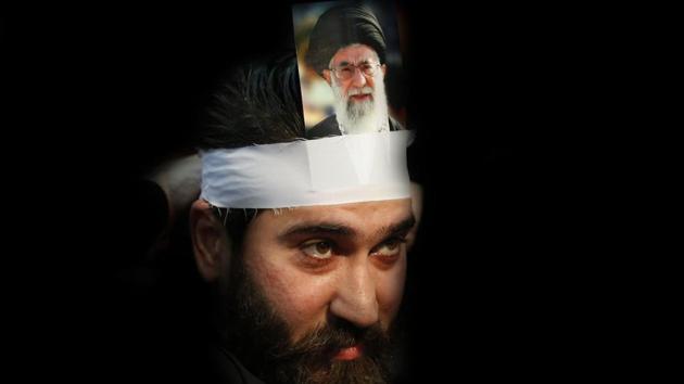 A Hezbollah supporter hangs a portrait on his head of Iran’s supreme leader Ayatollah Ali Khamenei, during a rally to commemorate the 40th anniversary of Iran’s Islamic Revolution, in southern Beirut, Lebanon, (Hussein Malla / AP)