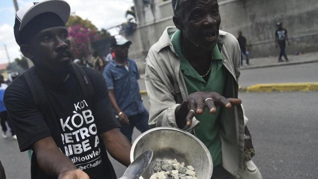 A protester shows a plate with stones, used to protest against the high price of food and consumer goods in Haiti, during a march through the streets of Port-au-Prince. (Hector Retamal / AFP)