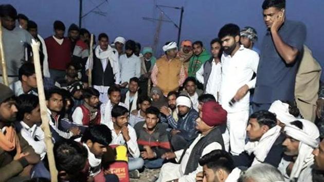 K S Bainsla along with Gujjar supporters sit on tracks at Malarna railway station to block railway route in Sawai Madhopur on Friday.(HT Photo)