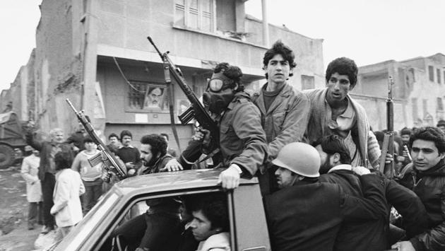 Armed rebels, one wearing a gas mask, ride in a truck near the headquarters of Ayatollah Khomeini in Tehran. Imperial guards were sent in to quell a pro-Khomeini demonstration by air force cadets in Farahabad on February 09. Islamists and leftist guerrillas fought imperial troops around the base the next day resulting in the troops’ retreat with heavy losses. (Campion / AP File) Armed rebels, one wearing a gas mask, ride in a truck near the headquarters of Ayatollah Khomeini in Tehran. Imperial guards were sent in to quell a pro-Khomeini demonstration by air force cadets in Farahabad on February 09. Islamists and leftist guerrillas fought imperial troops around the base the next day resulting in the troops’ retreat with heavy losses. (Campion / AP File)