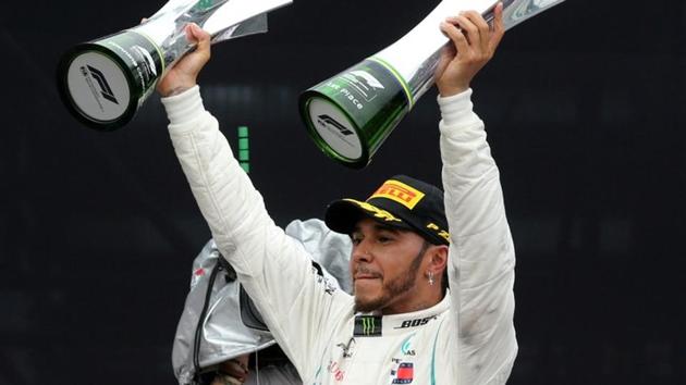 Mercedes' Lewis Hamilton celebrates after winning the race with the constructors championship trophy and the race trophy.(REUTERS)