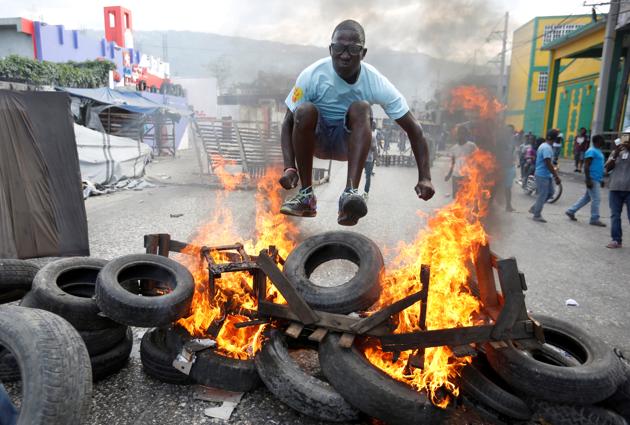 A protester jumps over a burning barricade during a protest against the government in the streets of Port-au-Prince, Haiti. (Jeanty Junior Augustin / REUTERS)