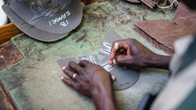 An employee of the Courteney boot company draws cut marks on the leather at the factory. The shoe business is based on a skilled workforce, traditional methods and decades-old stitching machines to produce classic outdoor boots and shoes. The company is named after Frederick Courteney Selous, the legendary explorer and hunter who died in 1917, and it is still owned by Gale Rice, widow of its founder John Rice. (Zinyange Auntony / AFP)