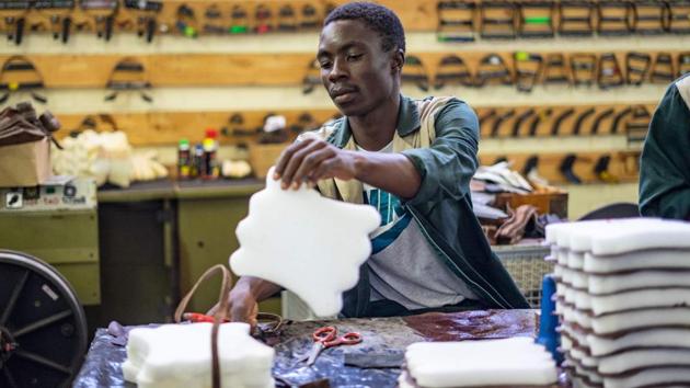 Employees give the final touch on a pair of shoes. In Bulawayo’s colonial-era city centre, Jay Giga, owner of a menswear store on Robert Mugabe Way, says he waits impatiently for each new batch of supplies.”A guy from South Africa came in yesterday and bought nine pairs for him and his friends,” Giga said.”I sell them as fast as I can get them in. We are always asking them to make more. (Zinyange Auntony / AFP)