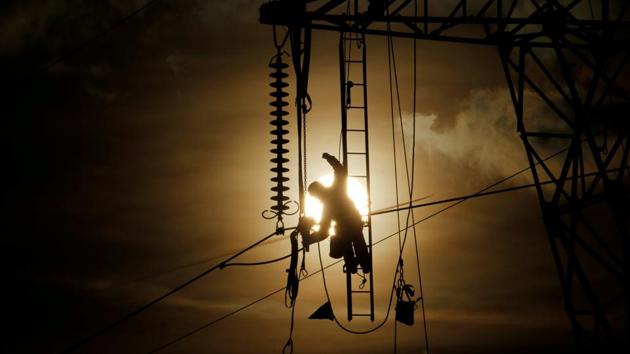 A technician works on an electricity pylon as part of maintenance of high-tension electricity power lines, during sunset in Roye, France. (Pascal Rossignol / REUTERS)