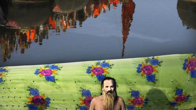 A naked Hindu holy man prays as others cross a pontoon bridge to take ritualistic dip on the auspicious day of Basant Panchami at Sangam, the confluence of sacred rivers the Yamuna, the Ganges and the mythical Saraswati, during the Kumbh Mela, in Prayagraj, Uttar Pradesh. (Rajesh Kumar Singh / AP Photo)