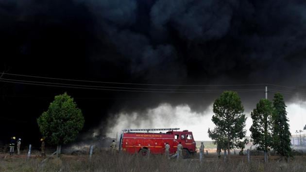 An Indian firefighter truck is pictured next to smoke coming from a massive industrial fire on the grounds of a paint factory on the outskirts of Bangalore, Karnataka. (Manjunath Kiran / AFP)
