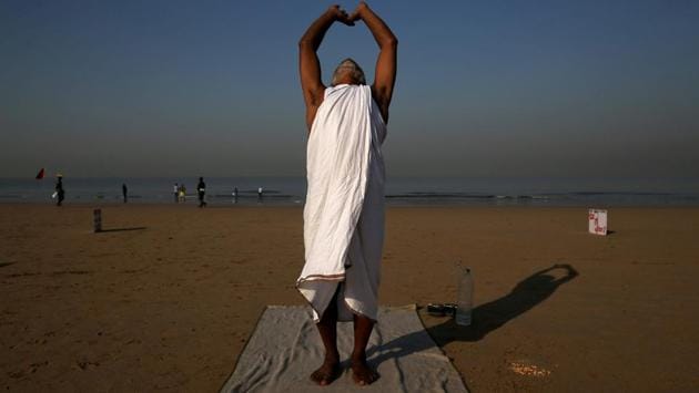 Krishna Das, 58, an Indian who according to local media has spent at least 10 years trying to spread messages for peace and harmony by placing placards on beaches, performs yoga after placing placards on a beach in Mumbai, Maharashtra. (Francis Mascarenhas / REUTERS)