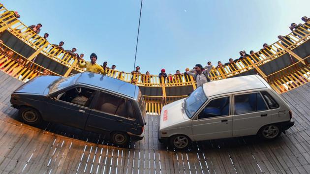 Stuntmen gesture at the crowd as they perform inside the 'well of death', in Prayagraj, Uttar Pradesh. (Arun Sharma / PTI)