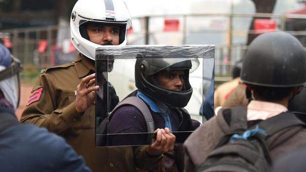 TOPSHOT - This photo taken on February 15, 2019 shows Delhi Traffic Police constable Sandeep Shahi (2L) holds up a mirror as part of a safety awareness campaign in New Delhi. - Sandeep Shahi, a traffic police constable in New Delhi, used to gift helmets to those riding some of the world's most dangerous streets with their head unprotected. But not anymore. By just showing a mirror to violators, Shahi has been able to tell them how a helmet is often the difference between life and death on the capital's notorious roads. (Photo by Prakash SINGH / AFP)(AFP)