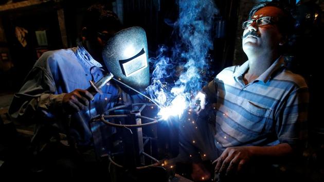 Workers weld an iron frame which will be used with a tractor for ploughing fields, at a workshop in an industrial area in Kolkata, West Bengal. (Rupak De Chowdhuri / REUTERS)