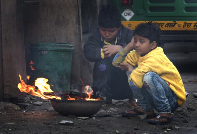 Children sit near fire to protect themselves from cold on a winter morning, at Indraprastha Extension, in New Delhi, India, on Sunday, January 27, 2019.(Sushil Kumar/HT FILE PHOTO)