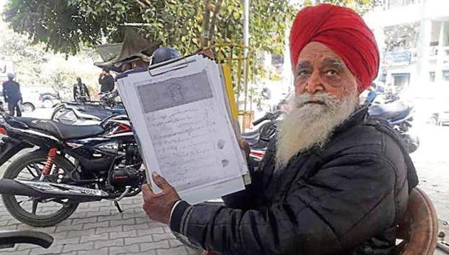 Kesar Singh, 84, showing an old land record in Urdu at his open-air office outside the Jalandhar district administrative complex. Sitting here since 2011, he charges ?500 for translating such documents to Punjabi, earning up to ?20,000 every month.(HT Photo)