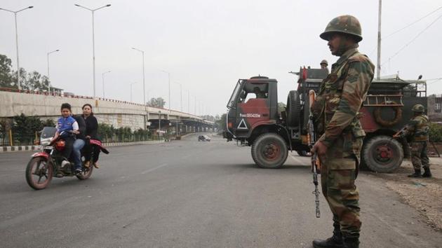 An Indian Army soldier stands guard as a family rides on a motorbike during a curfew in Jammu.(REUTERS)