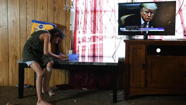 Rachel plays in the living room as President Donald Trump is shown on a newscast inside the family's trailer. An incensed U.S. President Donald Trump has called the migrants “a tremendous onslaught,” sent troops to the border, and pushed for tougher controls and a far more extensive border wall. (Loren Elliott / REUTERS)