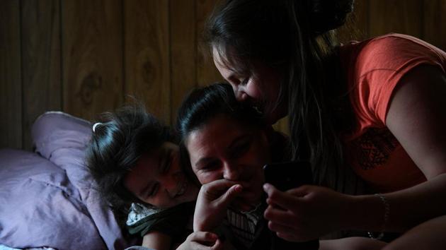 Orfa and her daughters, Rachel and Carolina video chat with the children's father who is in Honduras. The family is settling in Texico, but hanging over their heads is the decision yet to come on whether they can stay or must return to Honduras. Most asylum claims from Central Americans are ultimately rejected. (Loren Elliott / REUTERS)