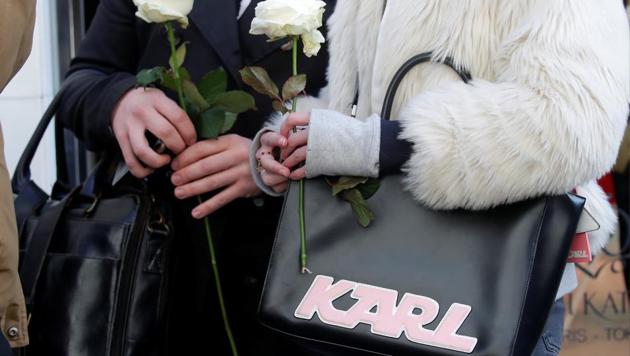 People hold white roses as they stand outside the Chanel fashion boutique after news that German haute-couture designer Karl Lagerfeld, artistic director at Chanel and an icon of the global fashion industry for over half a century, has died, aged 85, in Paris, France, February 19, 2019.(REUTERS/Charles Platiau)