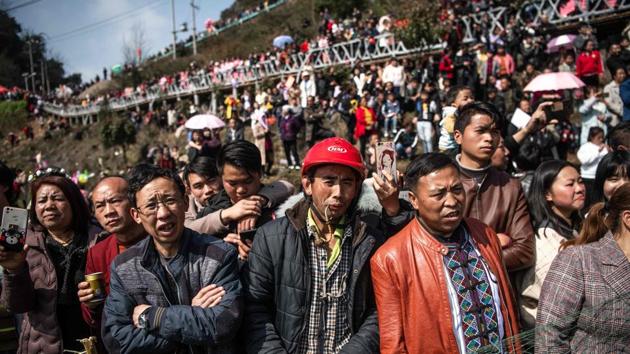 Onlookers watch the performance with smartphones in their hands as the women swirl across a meadow, wearing dresses and jackets embroidered with pink roses and geometric patterns. (Fred Dufour / AFP)