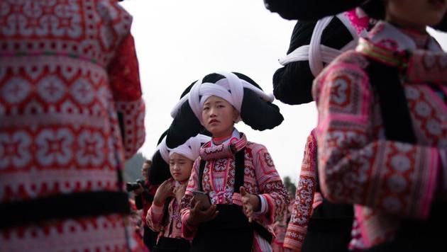 Girls from the Long Horn Miao, a branch of the Miao ethnic minority group, prepare to take part in the annual flower festival or 'Tiaohuajie' in the village of Longjia in China's Guizhou province. - Against a stunning mountain backdrop, dozens of girls and women of the Long Horn Miao ethnicity performed for the annual celebration held in Guizhou province on the 10th day of the Lunar New Year -- the Year of the Pig. (Fred Dufour / AFP )