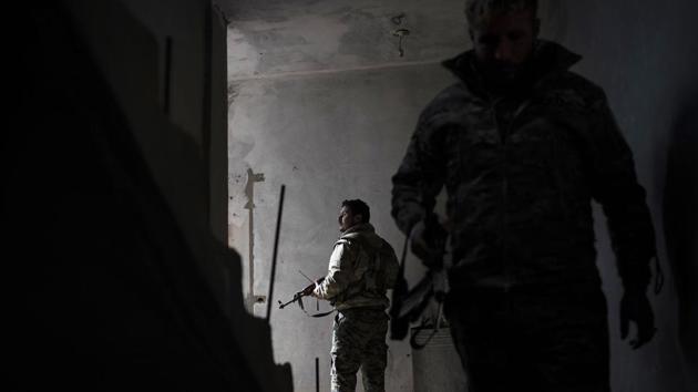 US-backed Syrian Democratic Forces (SDF) fighters walk in a building as fight against Islamic State militants continue in the village of Baghouz, Syria. The Islamic State group has been reduced from its self-proclaimed caliphate that once spread across much of Syria and Iraq at its height in 2014 to a speck of land on the countries' shared border. (Felipe Dana / AP)