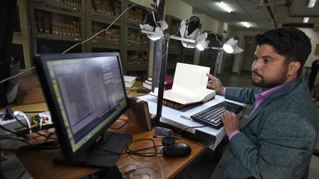 A man works inside Central Library during the digitisation process. In the absence of a proper a digitisation setup on the campus, the entire process was done using DSLR cameras in collaboration with Iran Culture House in Delhi. (Burhaan Kinu / HT Photo)