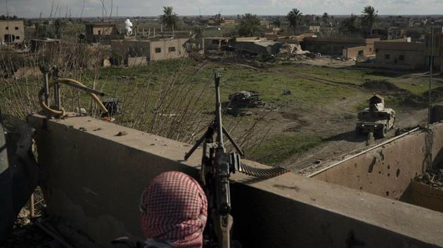 A Syrian Democratic Forces (SDF) fighter stands atop a building used as a temporary base near the last land still held by Islamic State militants in Baghouz, Syria. This is the last speck of land held by the Islamic State group — a patch along the Euphrates River in eastern Syria where an estimated 300 militants are mixed in with hundreds of civilians, refusing to surrender and trying to negotiate an exit with the SDF surrounding them. (Felipe Dana / AP)