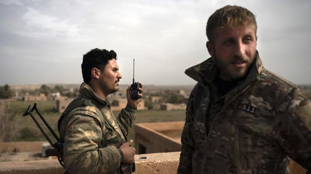 SDF fighters talk on a radio in a rooftop position as fight against Islamic State militants continues. The SDF can’t assault the site or call in airstrikes because of the civilians. The fighters have seen the militants moving civilians around at gunpoint as protection. (Felipe Dana / AP)