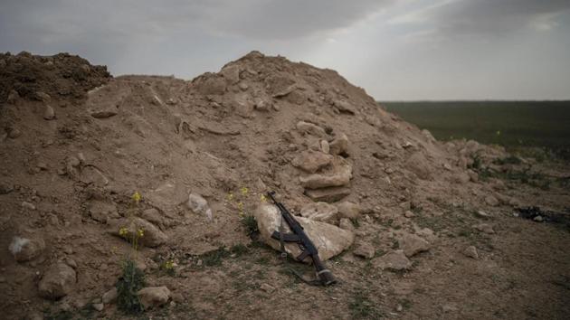 An AK-47 rifle, belonging to an SDF fighter, rests on a rock on a hill in the desert outside the village of Baghouz. Activists said a truce in place has been extended for five days as of Sunday. A person familiar with ongoing deliberations said the group has asked for an exit through a corridor to the rebel-held northwestern province of Idlib and demand to be allowed to leave along with the civilians. (Felipe Dana / AP)