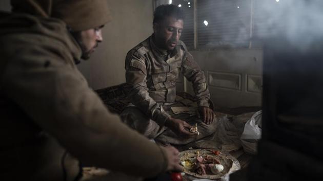 SDF fighters eat in a building as the fight against Islamic State militants continues. The SDF appears to be aiming to wait the militants out. “They don’t have supplies in the area they are in that would last for a week or more,” said Baran, the commander. (Felipe Dana / AP)